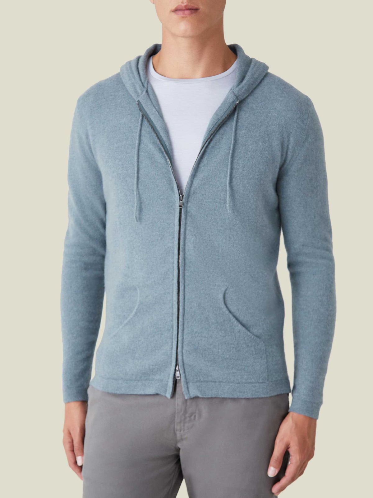 Model seen from the front wearing the French Blue Cashmere Zip Hoodie, styled open with a white t-shirt and grey trousers.