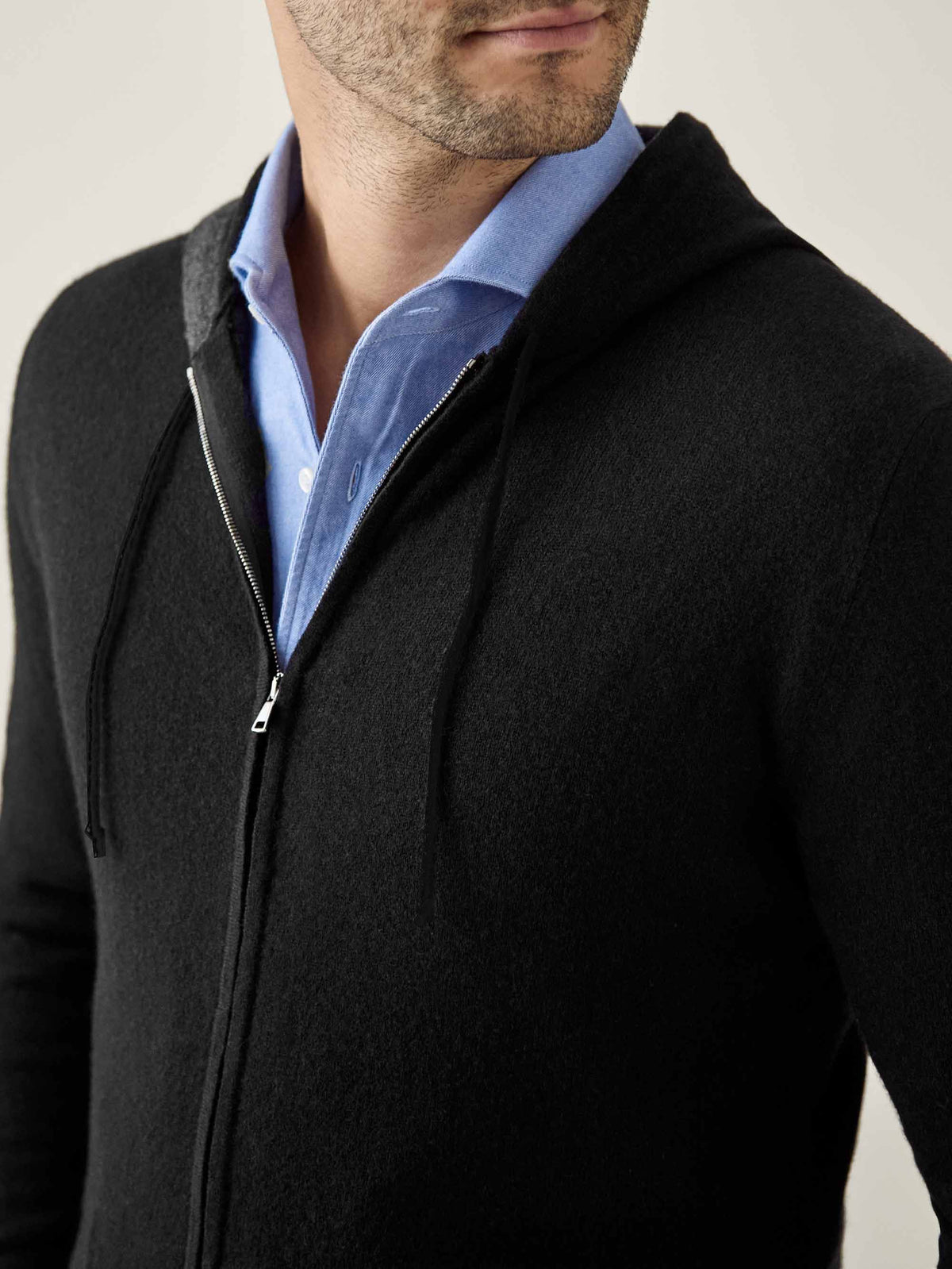 A close-up of a man wearing the Black Cashmere Zip Hoodie over a light blue shirt, showing the fabric texture and zip detail.