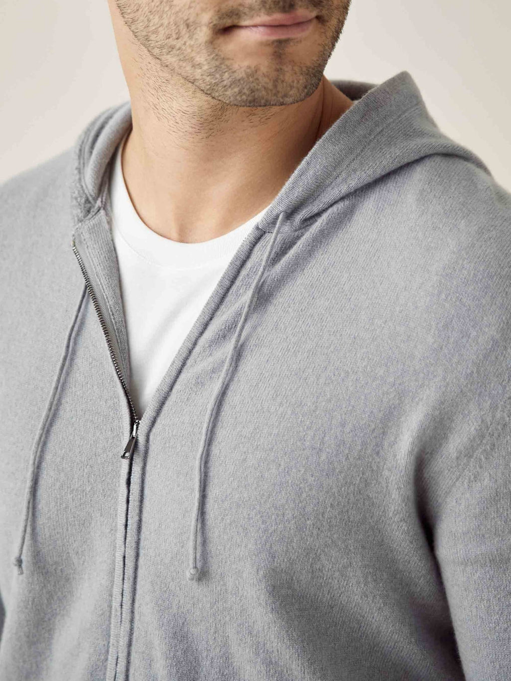 Close-up of a man wearing the misty grey cashmere zip hoodie, highlighting the soft texture and silver zip detail.