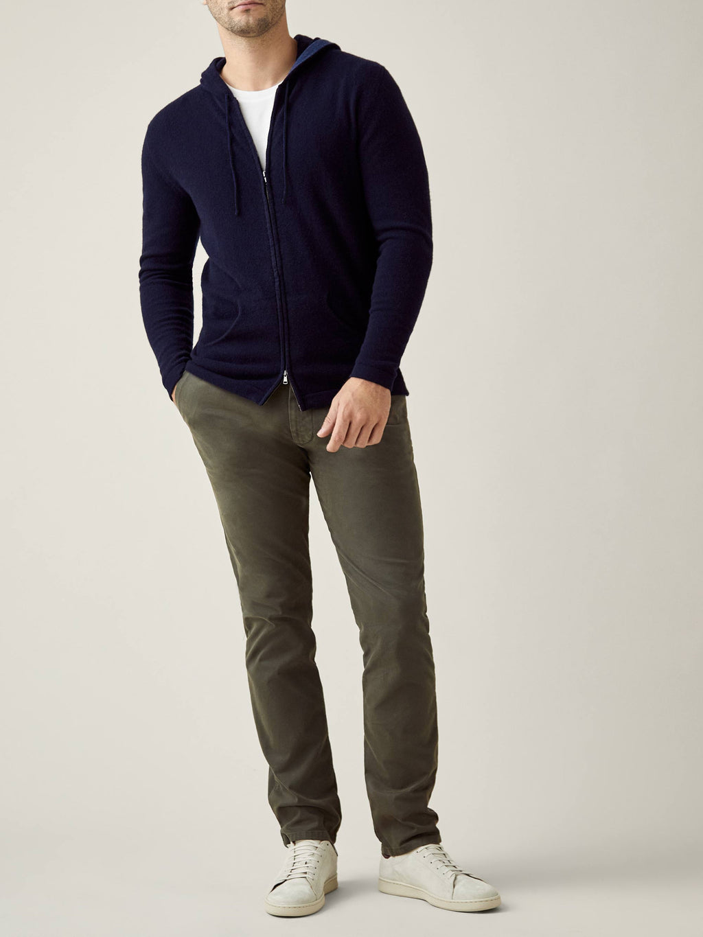 A model showcases the Midnight Blue Cashmere Zip Hoodie, styled open with a white t-shirt, olive chinos, and white sneakers.