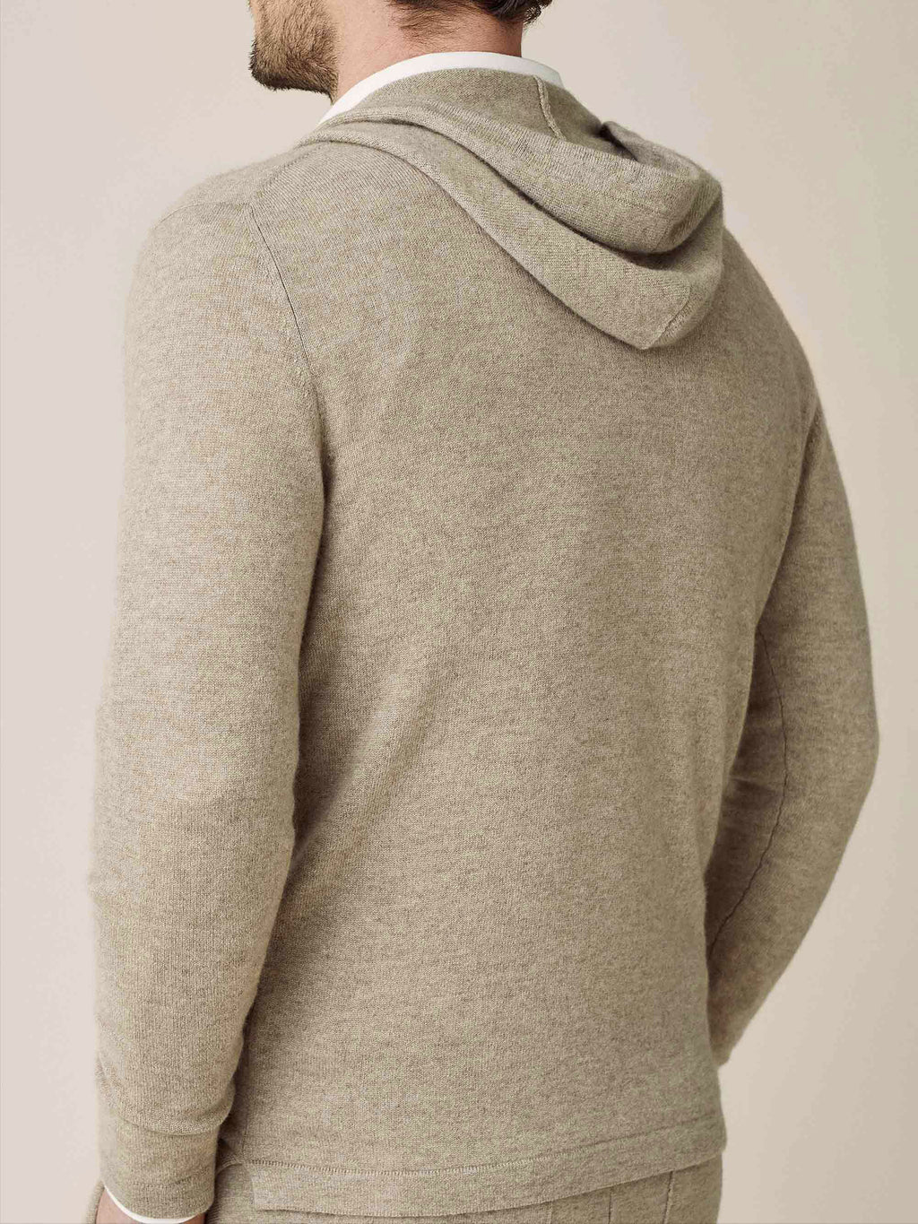 Back view of a model wearing the camel beige cashmere zip hoodie, showcasing the hood and soft texture of the knit.
