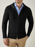 A model wears a black cashmere zip hoodie layered over a light blue collared shirt and beige chinos.