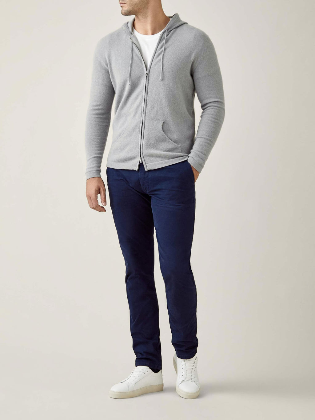 Full-body shot of a model wearing Luca Faloni's Misty Grey Cashmere Zip Hoodie with navy trousers and white sneakers.