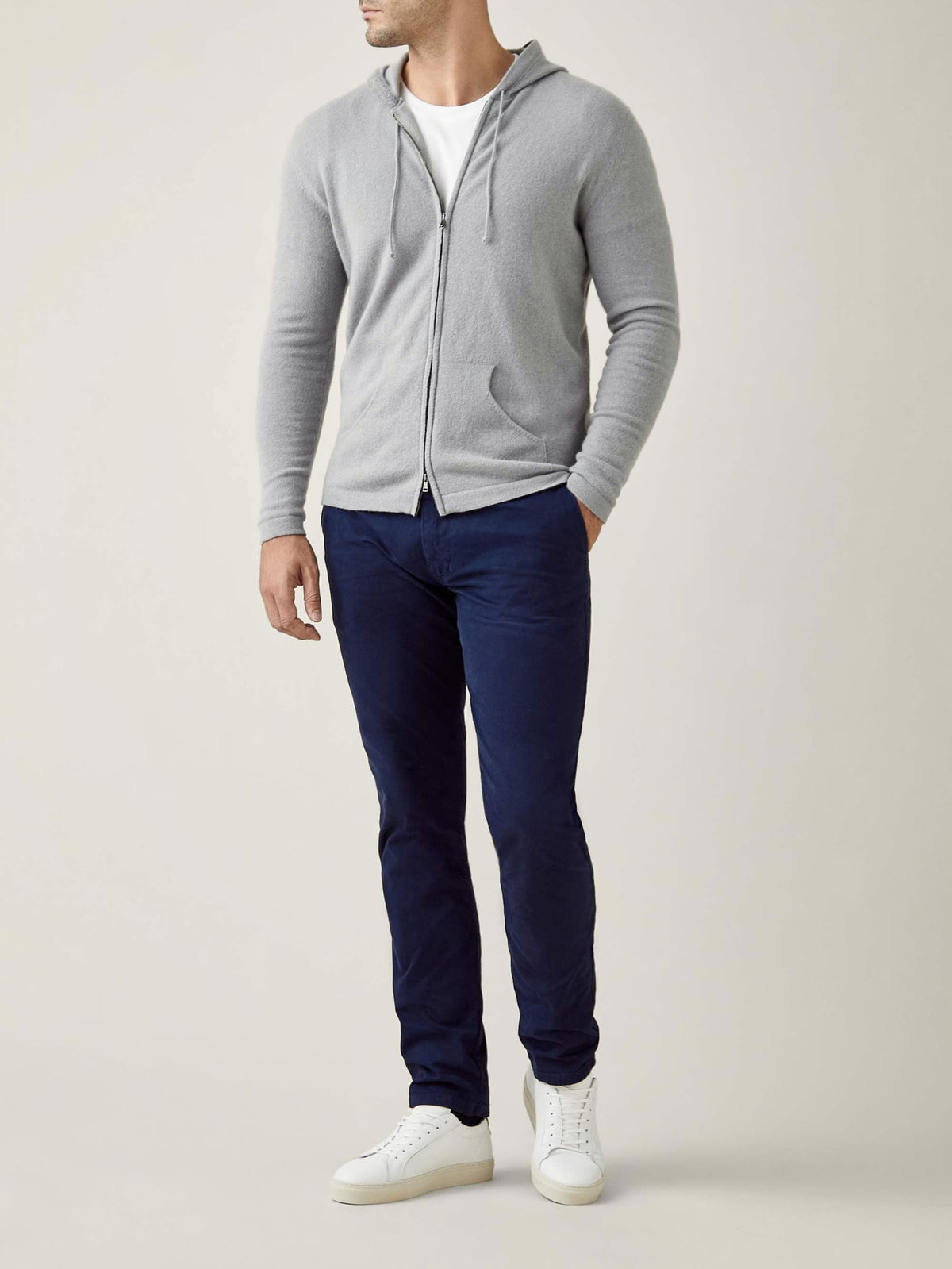 Full-body shot of a model wearing Luca Faloni's Misty Grey Cashmere Zip Hoodie with navy trousers and white sneakers.