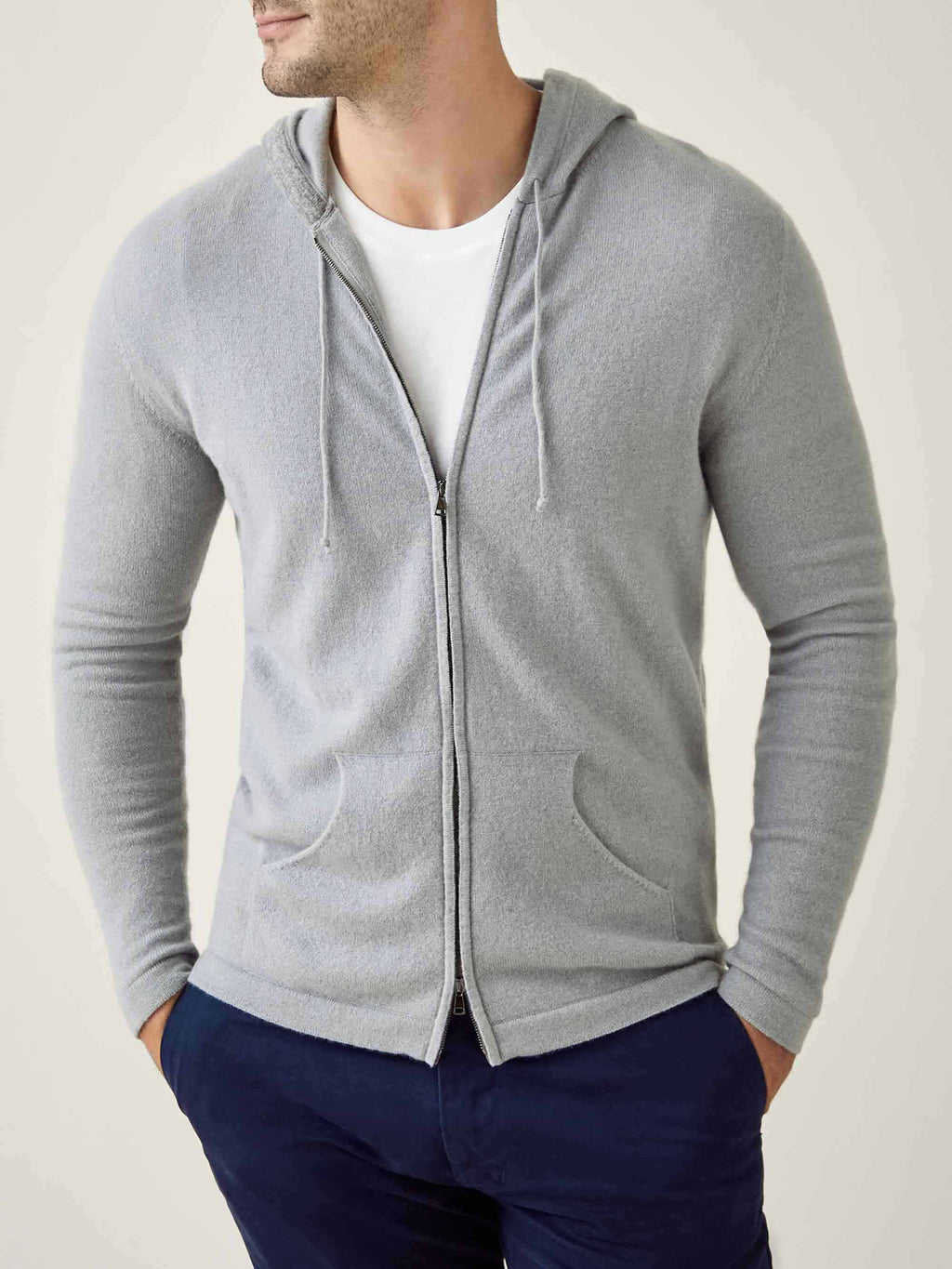 Front view of a model wearing the Misty Grey Cashmere Zip Hoodie, layered over a white t-shirt and paired with dark trousers.