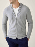 Front view of a model wearing the Misty Grey Cashmere Zip Hoodie, layered over a white t-shirt and paired with dark trousers.