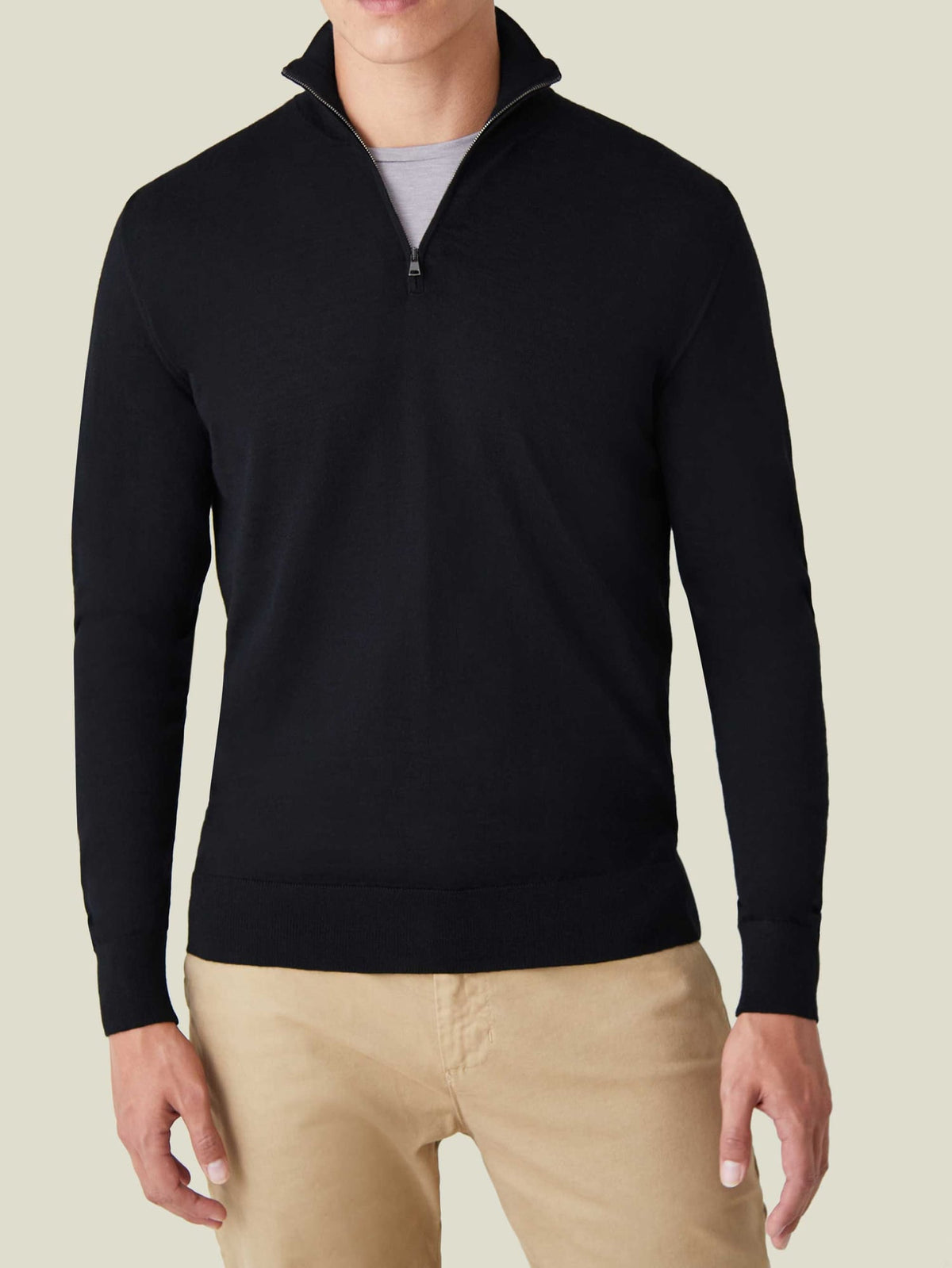 Front view of a model wearing the Black Silk-Cashmere Zip-up, layered over a t-shirt with tan chinos.