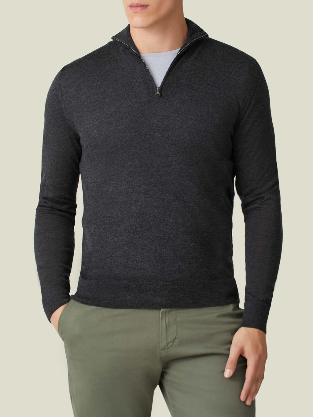 A man wearing the Luca Faloni Silk-Cashmere Zip-up in Charcoal Grey, layered over a t-shirt and paired with green chinos.