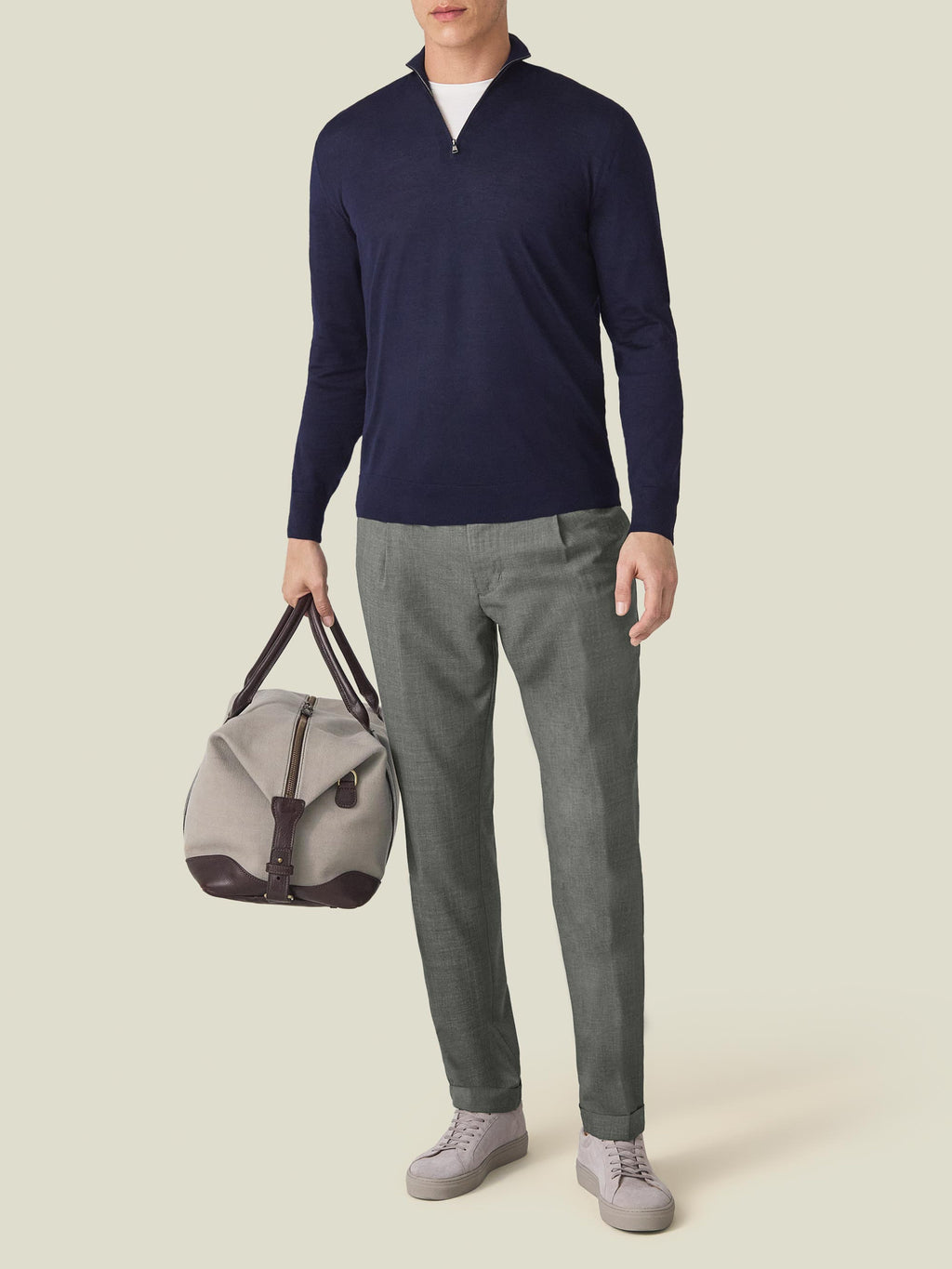 Full-length view of a man wearing the navy blue Silk-Cashmere Zip-up with grey trousers, holding a weekend bag.