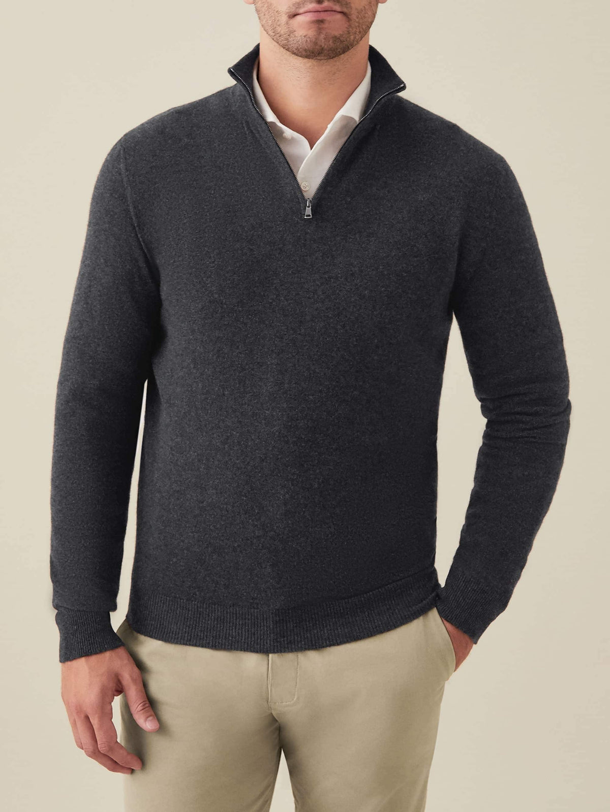 Man wearing the Luca Faloni charcoal grey cashmere zip-up over a white collared shirt and beige chinos.