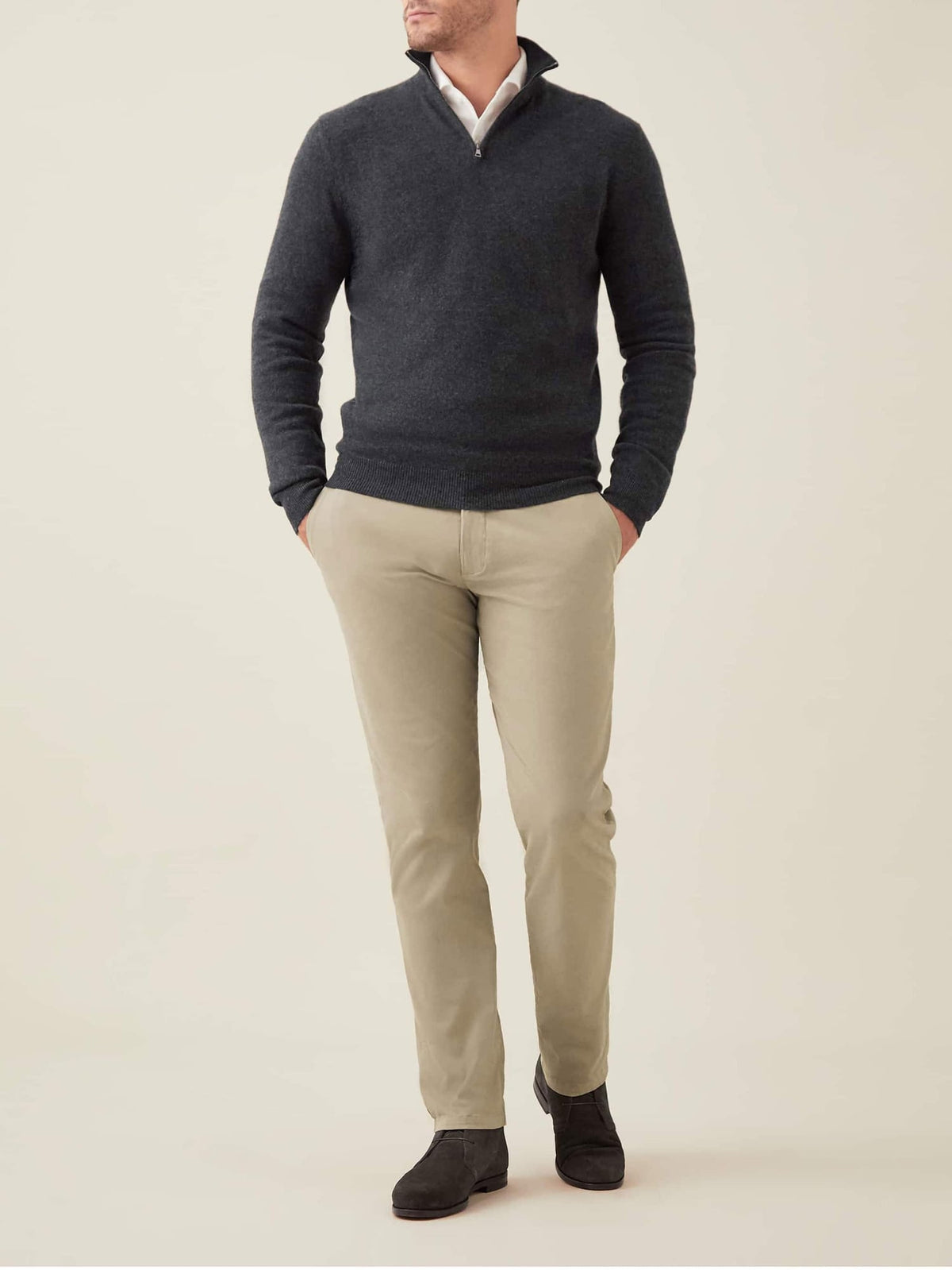 Full length shot of a model wearing the charcoal grey cashmere zip-up with beige trousers and dark shoes.
