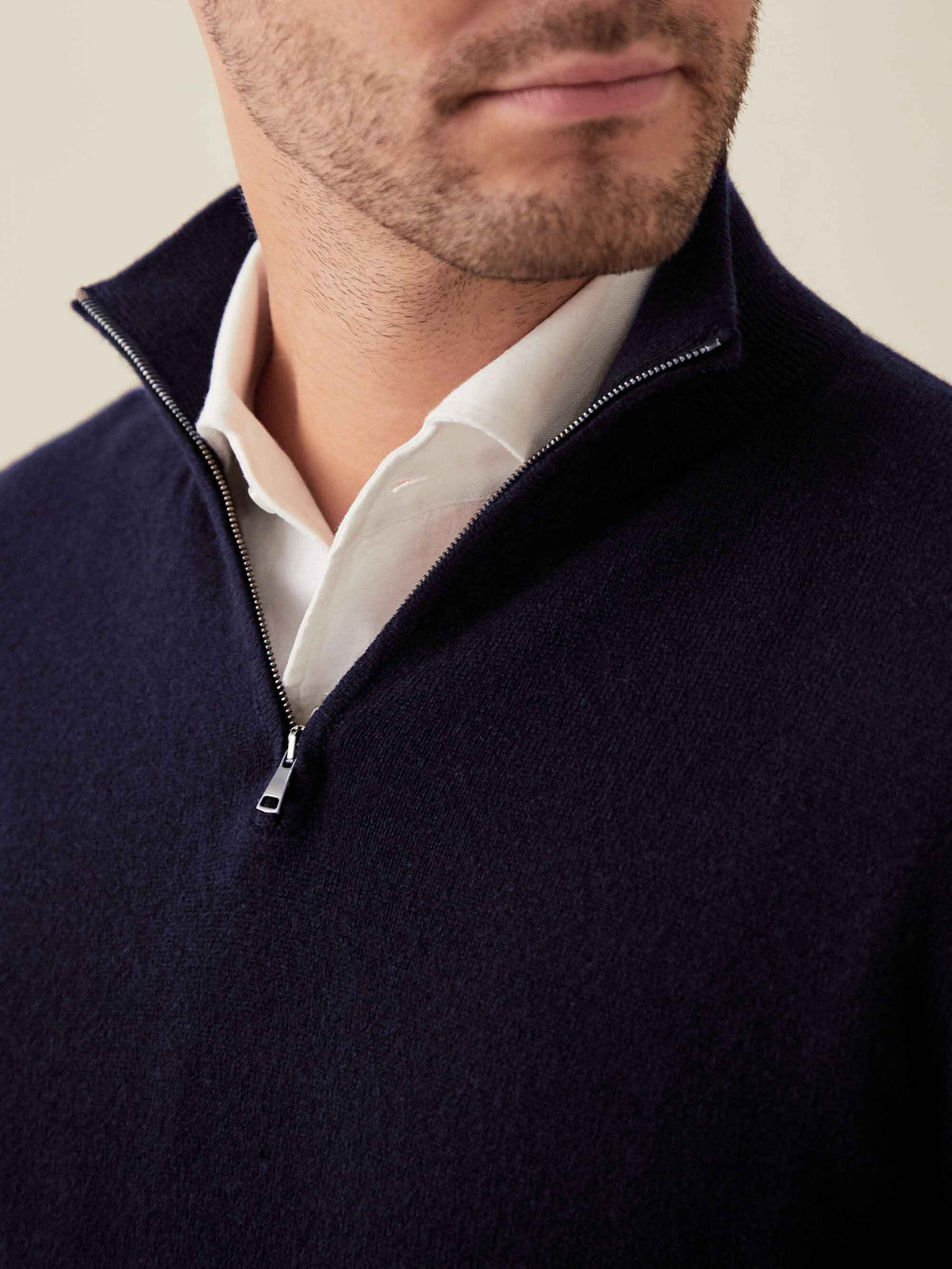 Close-up of a man wearing a midnight blue cashmere zip-up over a white shirt, showing the funnel collar and zipper detail.