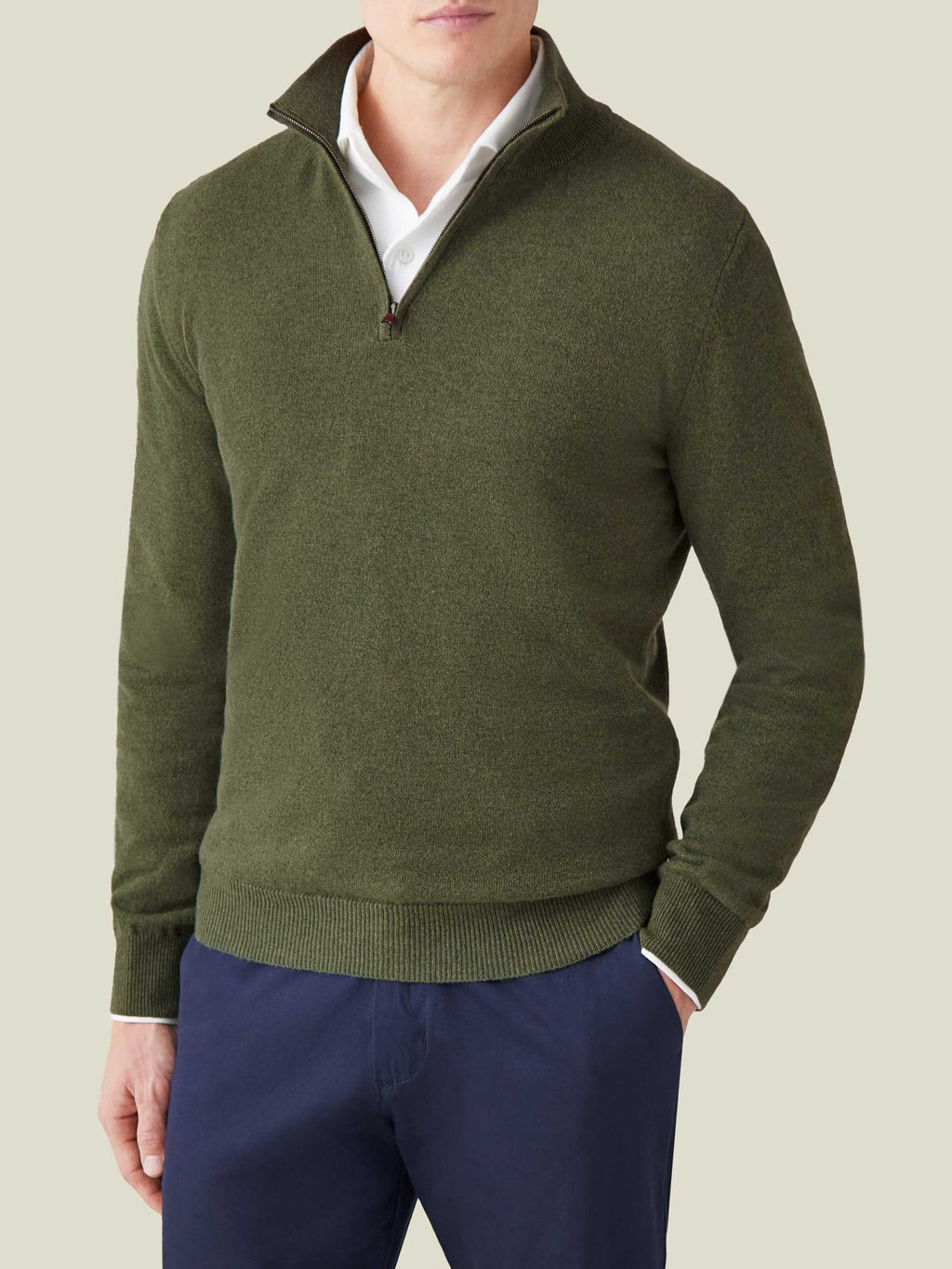 Model wearing Luca Faloni's hunting green cashmere zip-up, styled over a white collared shirt and navy trousers.