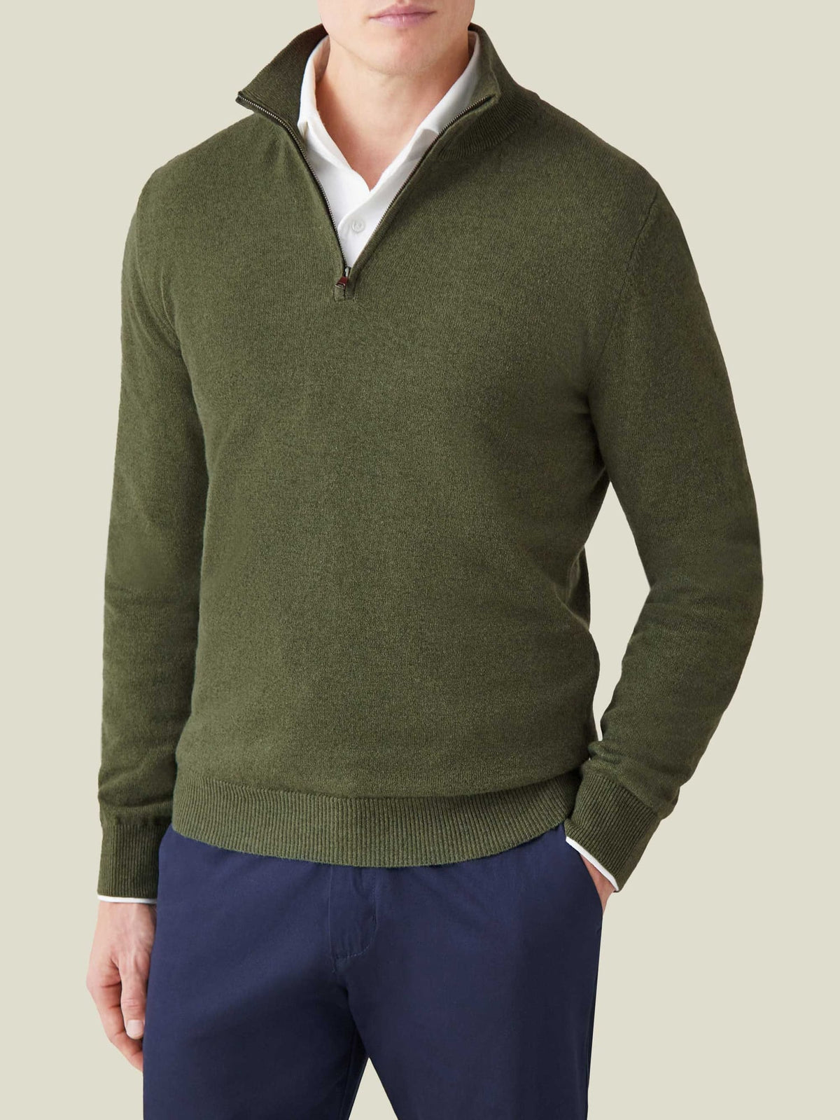 Model wearing Luca Faloni's hunting green cashmere zip-up, styled over a white collared shirt and navy trousers.