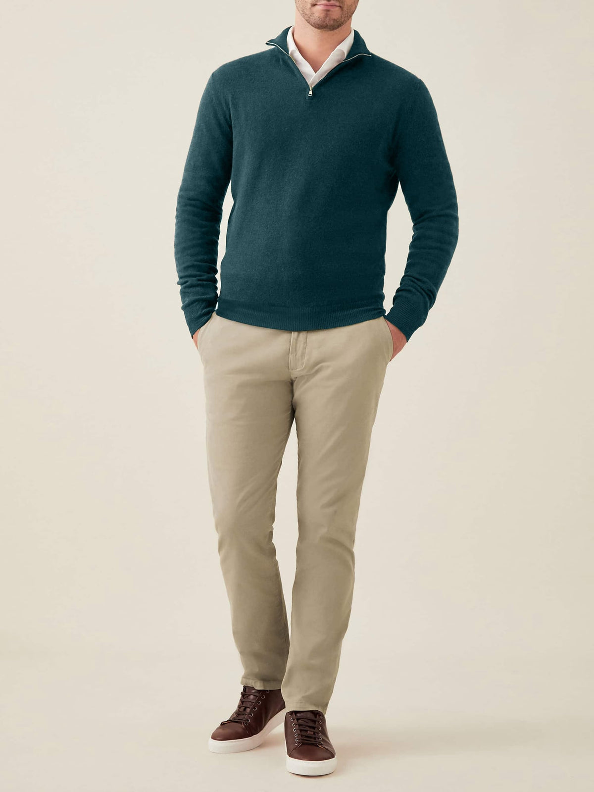 Model wears a forest green cashmere zip-up sweater over a white shirt, paired with beige chinos.