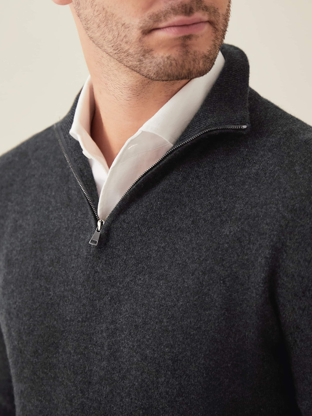 Close-up detail of a model wearing the charcoal grey cashmere zip-up, focusing on the quarter-zip and funnel collar.