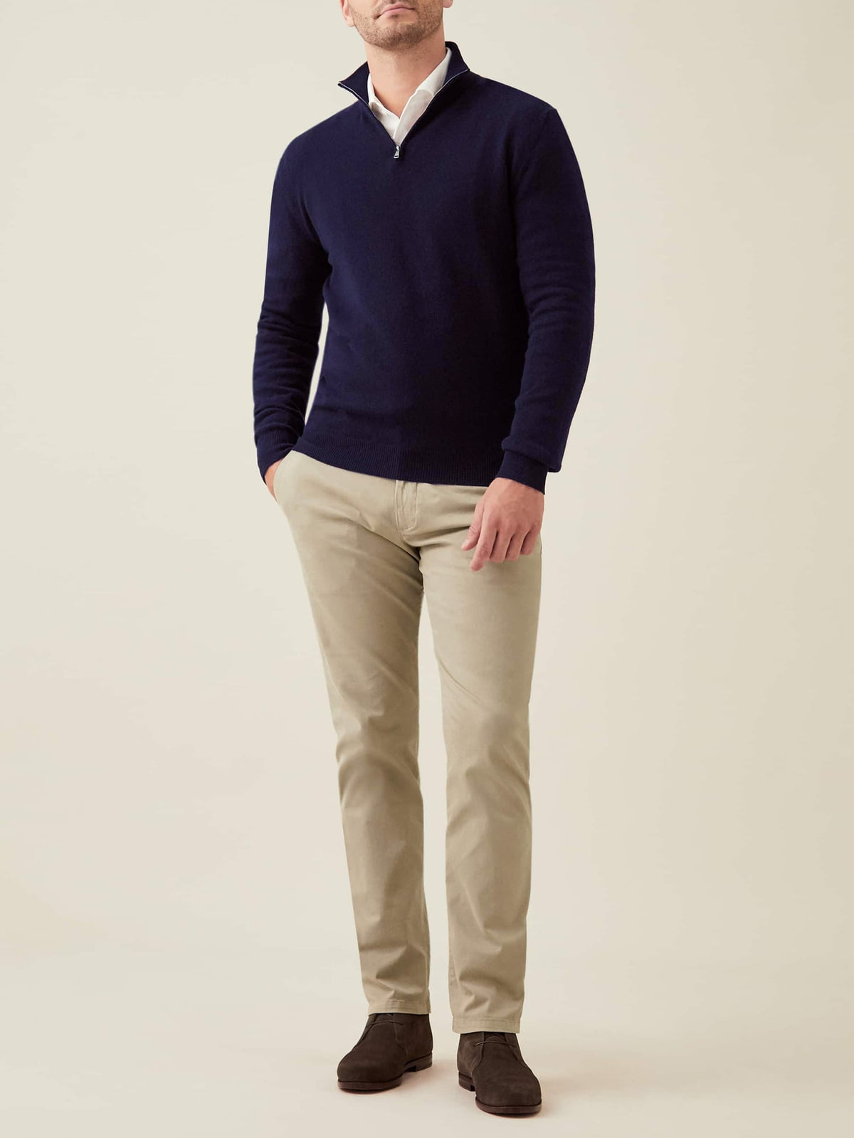 Full-length shot of a man wearing the Luca Faloni midnight blue cashmere zip-up with beige chinos and dark brown shoes.