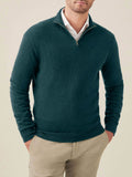 A man wears a forest green cashmere quarter-zip sweater over a white collared shirt and beige chinos, seen from the front.