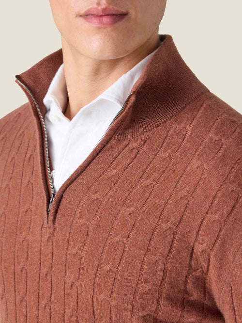 Close-up of the rust cashmere Cable Knit Zip-up, detailing the knit texture, funnel collar, and quarter-zip.