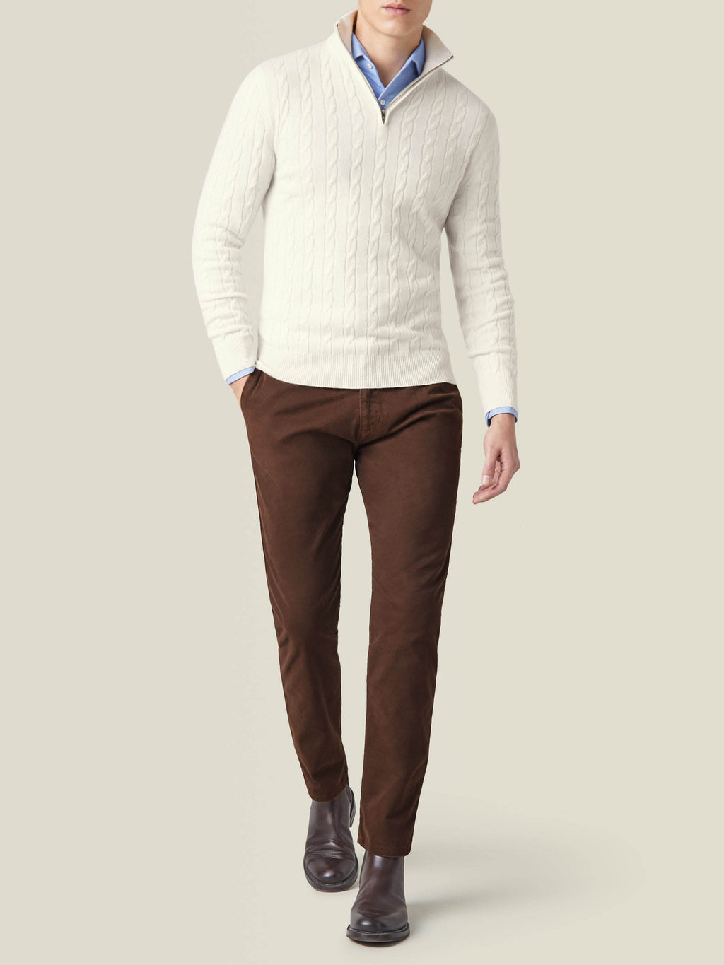 Full-length view of a model wearing the Ivory Cable Knit Zip-up, styled with brown trousers and dark boots.