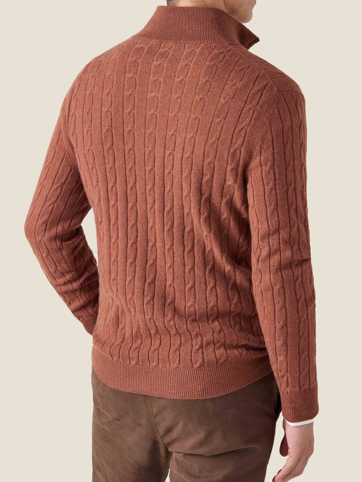 Back view of a man wearing a rust cashmere Cable Knit Zip-up, showing the detailed cable knit texture.