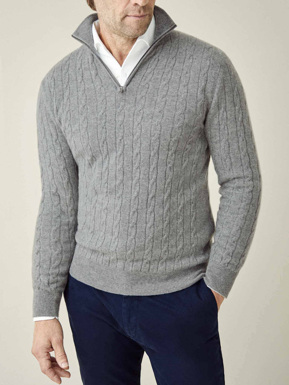 A man wears the Cable Knit Zip-up in Dolomiti Grey cashmere over a white shirt.