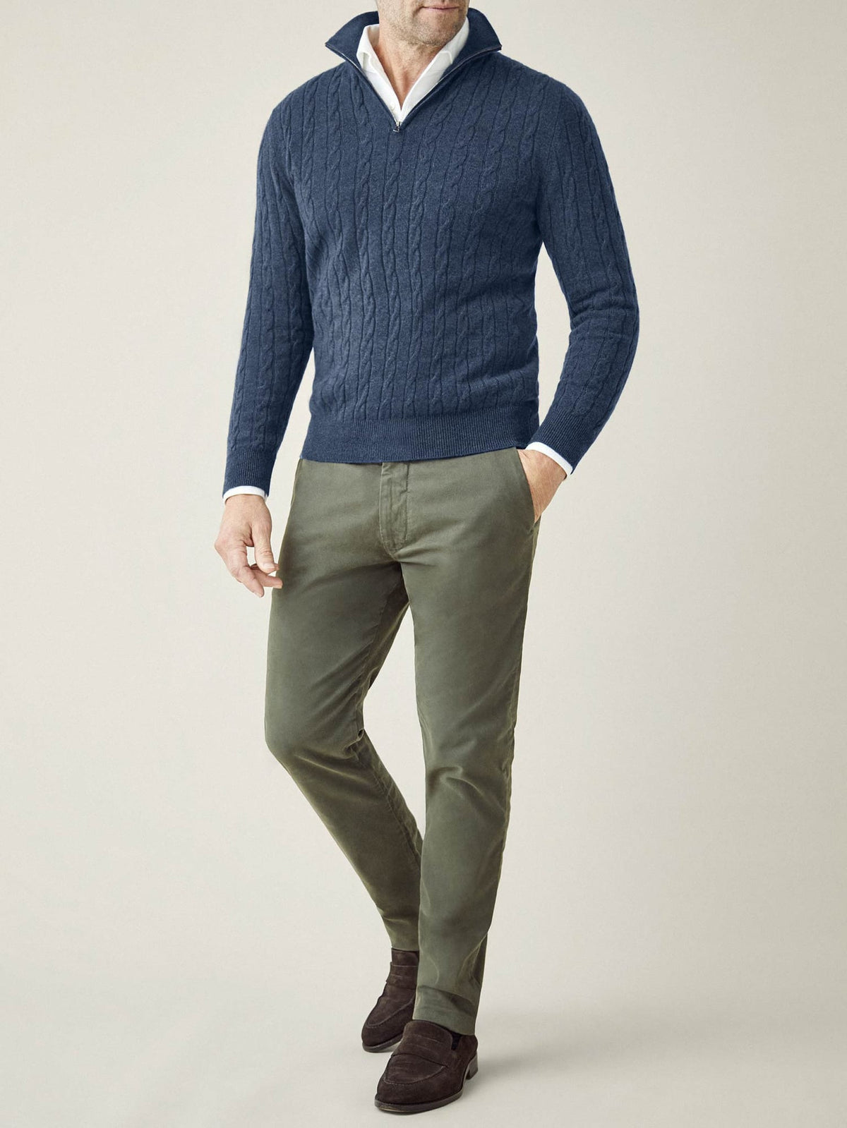 Model wears the Atlantic Blue Cashmere Cable Knit Zip-up with a white collared shirt and green trousers.