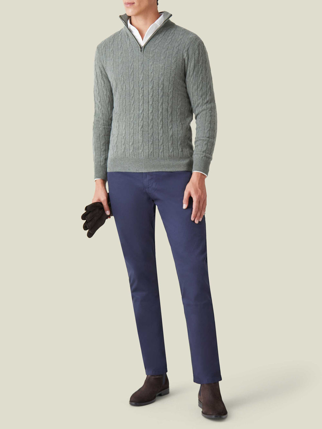 Model wearing the Moss Green Cashmere Cable Knit Zip-up, styled with navy trousers and boots on a neutral background.
