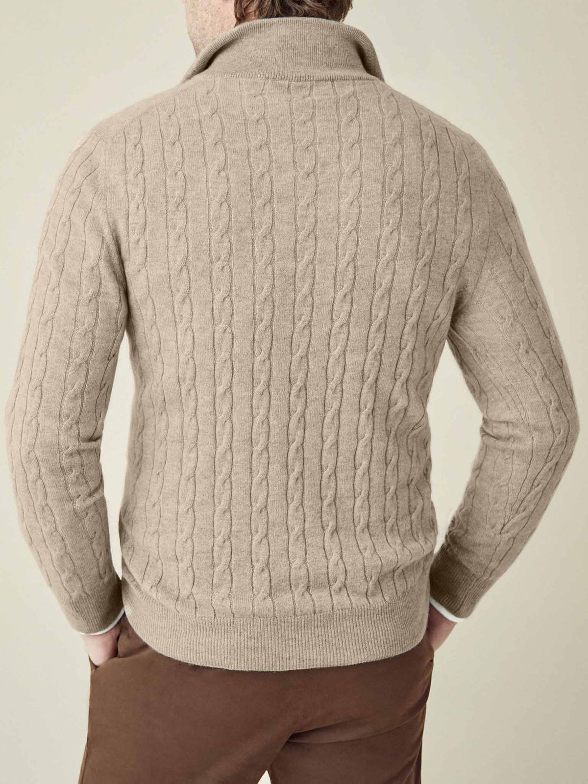 Rear view of a man wearing the Cable Knit Zip-up in Camel Beige, showcasing the intricate knit texture and ribbed hem.