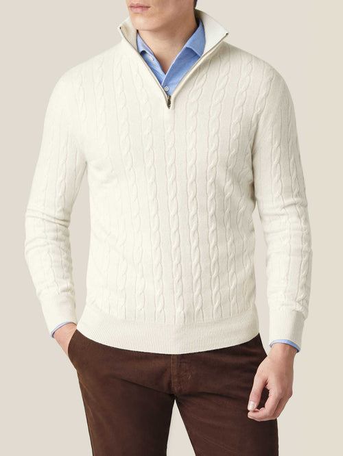 Man wearing the Luca Faloni ivory cashmere cable knit zip-up over a blue shirt and paired with brown trousers.