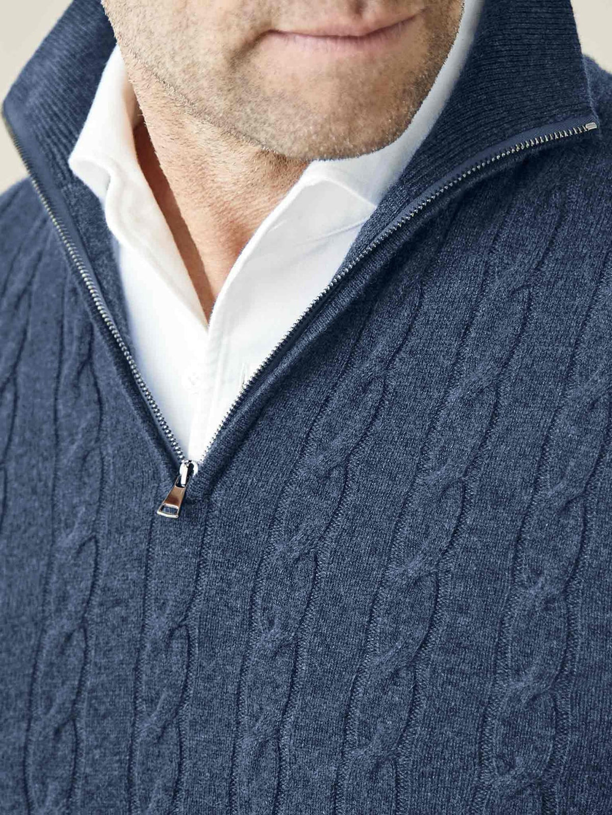 A close-up shot of a model wearing the Atlantic Blue Cashmere Cable Knit Zip-up, showcasing the zip and collar detail.
