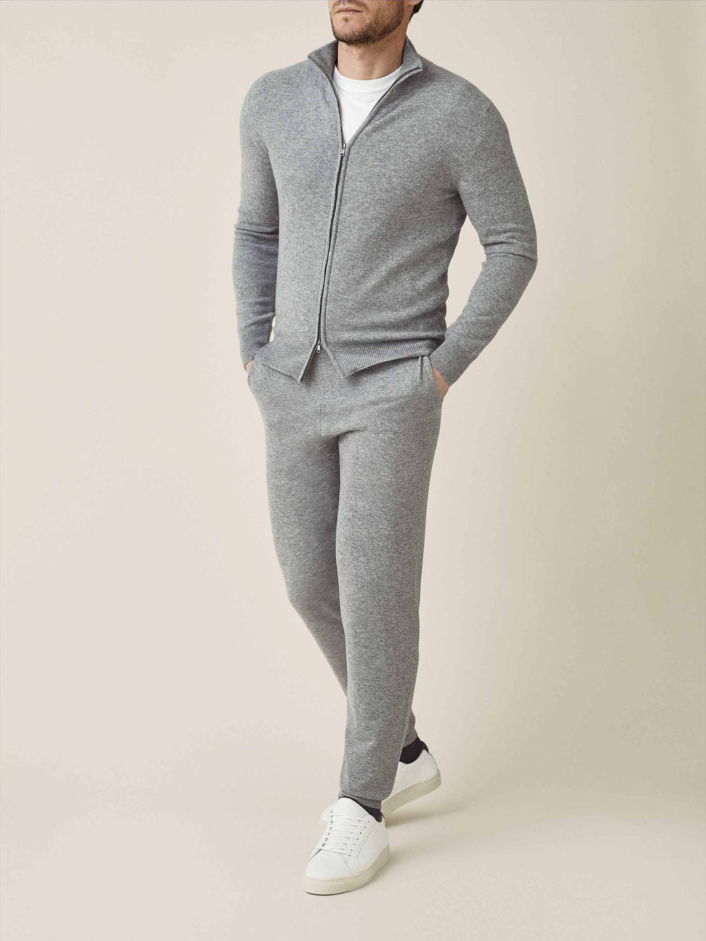 Front view of a model wearing the Dolomiti Grey Cashmere Joggers with a matching zip-up hoodie and white sneakers.