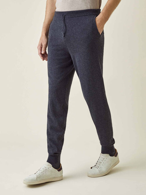 Side profile of a model wearing Luca Faloni's tapered charcoal grey cashmere joggers, styled with white sneakers.