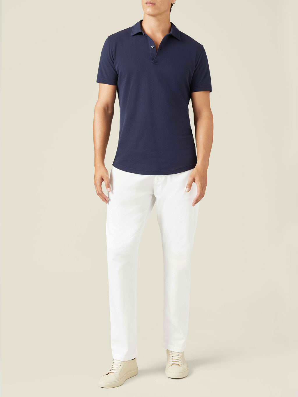 Front view of a model wearing the navy blue Classic Piqué Polo with white trousers and cream sneakers.