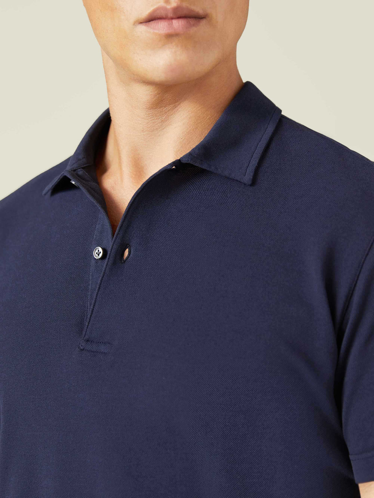 A close-up of a model wearing the Navy Blue Classic Piqué Polo, showing the detail of the collar, placket, and fabric.