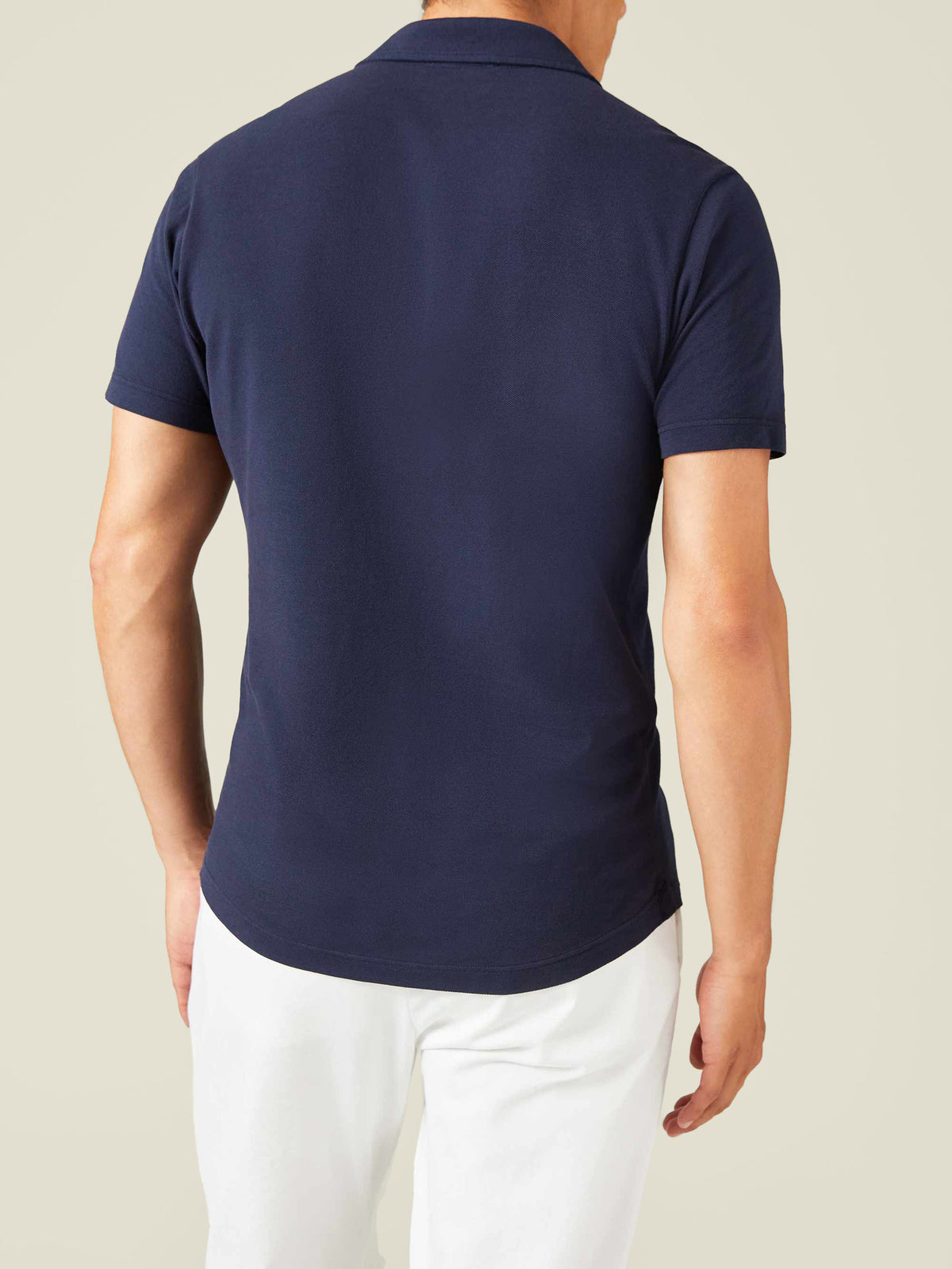 Rear view of a model wearing the Classic Piqué Polo in navy blue, highlighting the tailored fit and curved hemline.