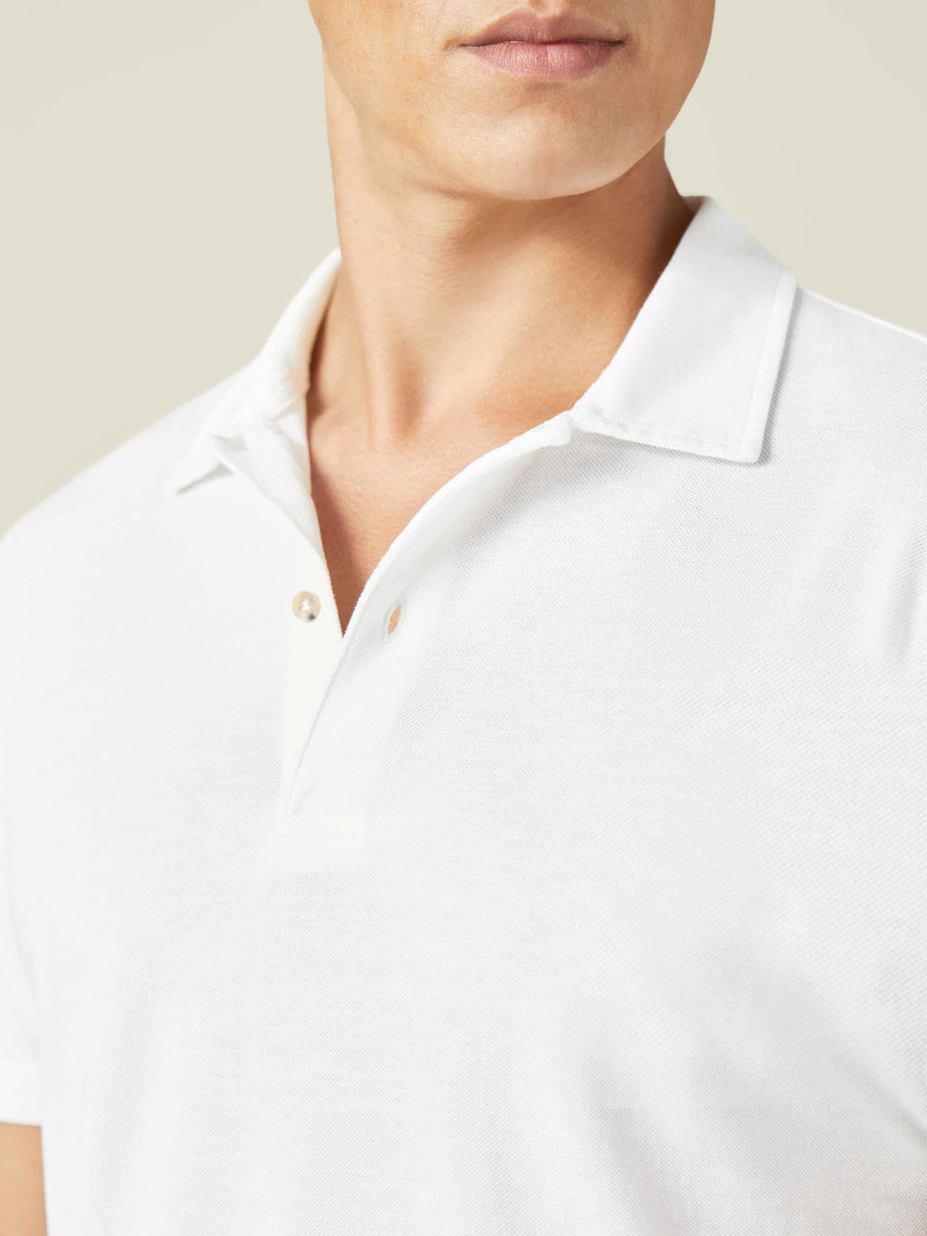 Close-up on a model wearing the white Classic Piqué Polo, highlighting the collar, placket and fine piqué texture.