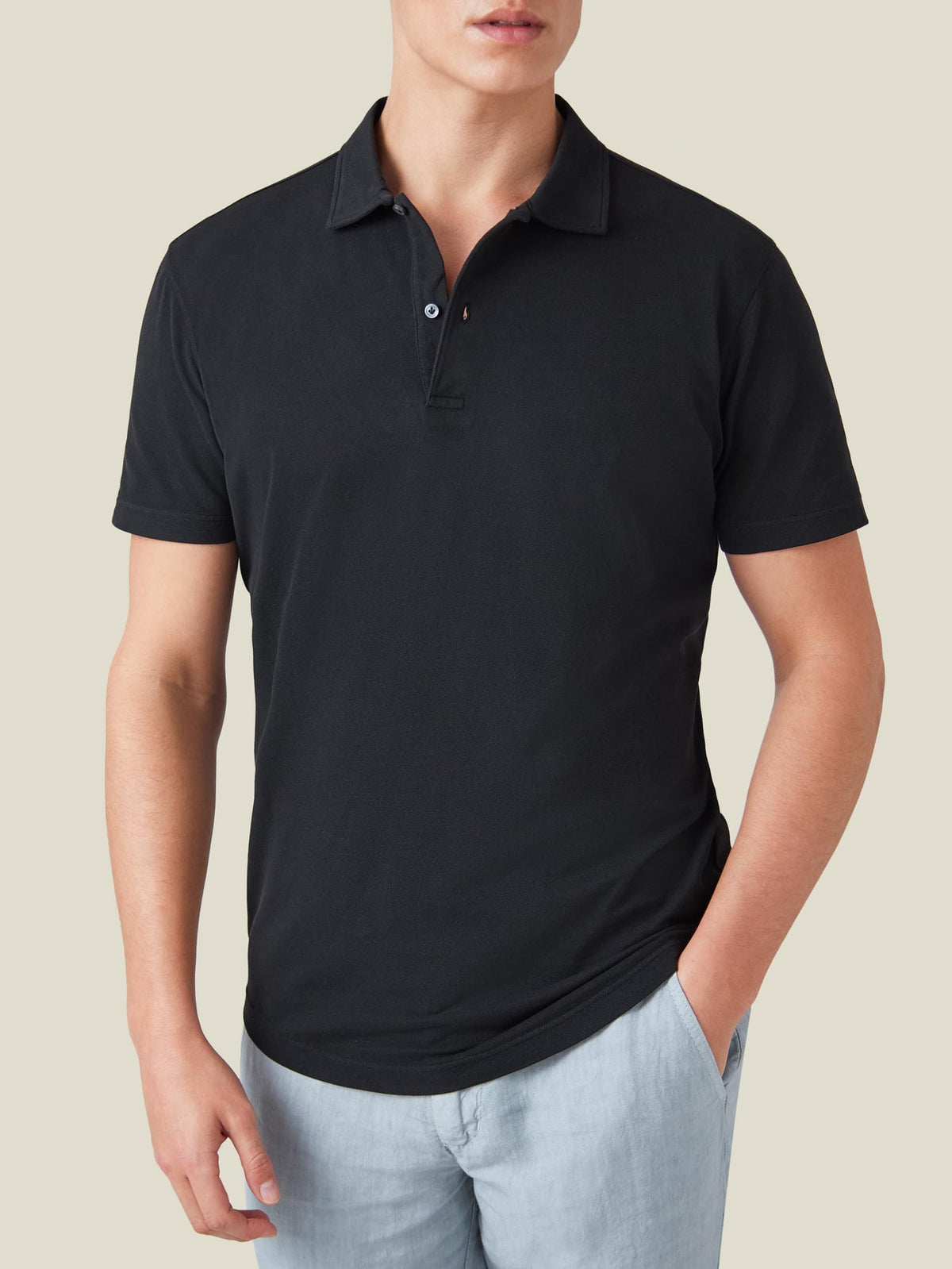Front view of a model wearing the Classic Piqué Polo in black by Luca Faloni, styled with light blue trousers.