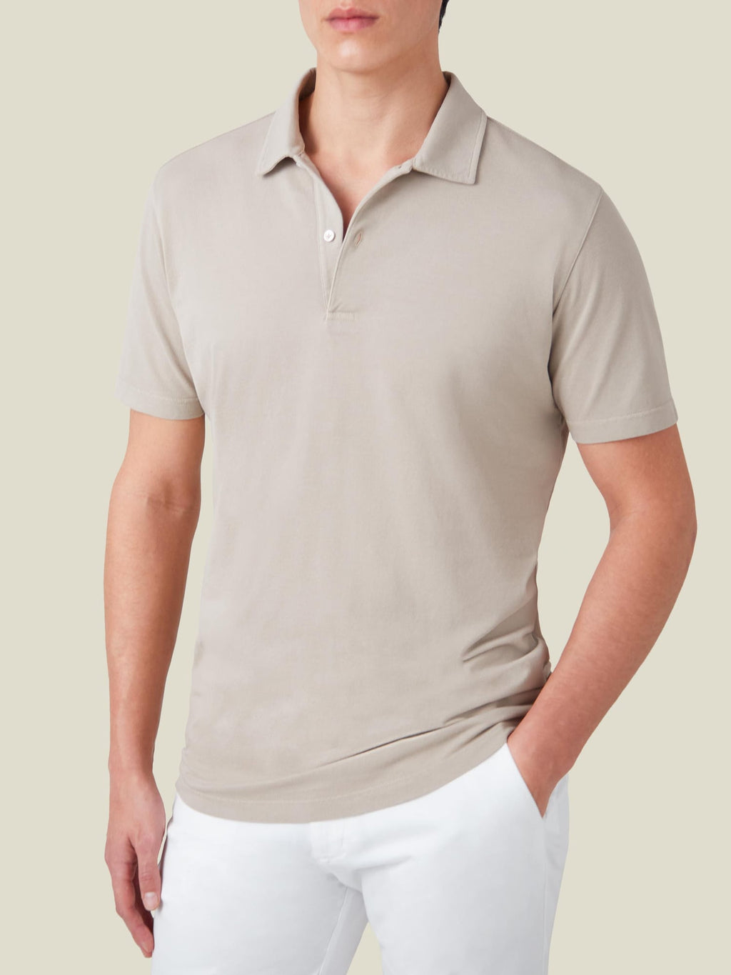 Front view of a man wearing Luca Faloni's oatmeal cotton piqué polo shirt with white trousers.