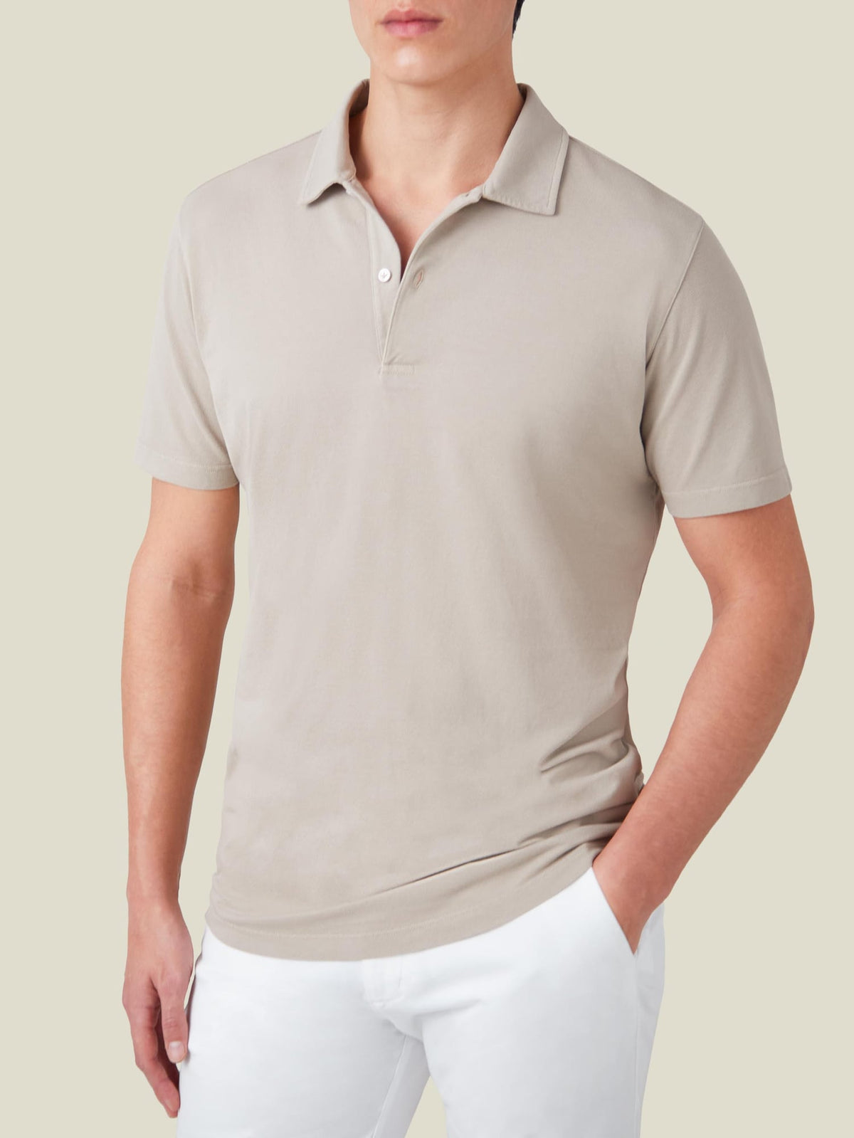 Front view of a man wearing Luca Faloni's oatmeal cotton piqué polo shirt with white trousers.