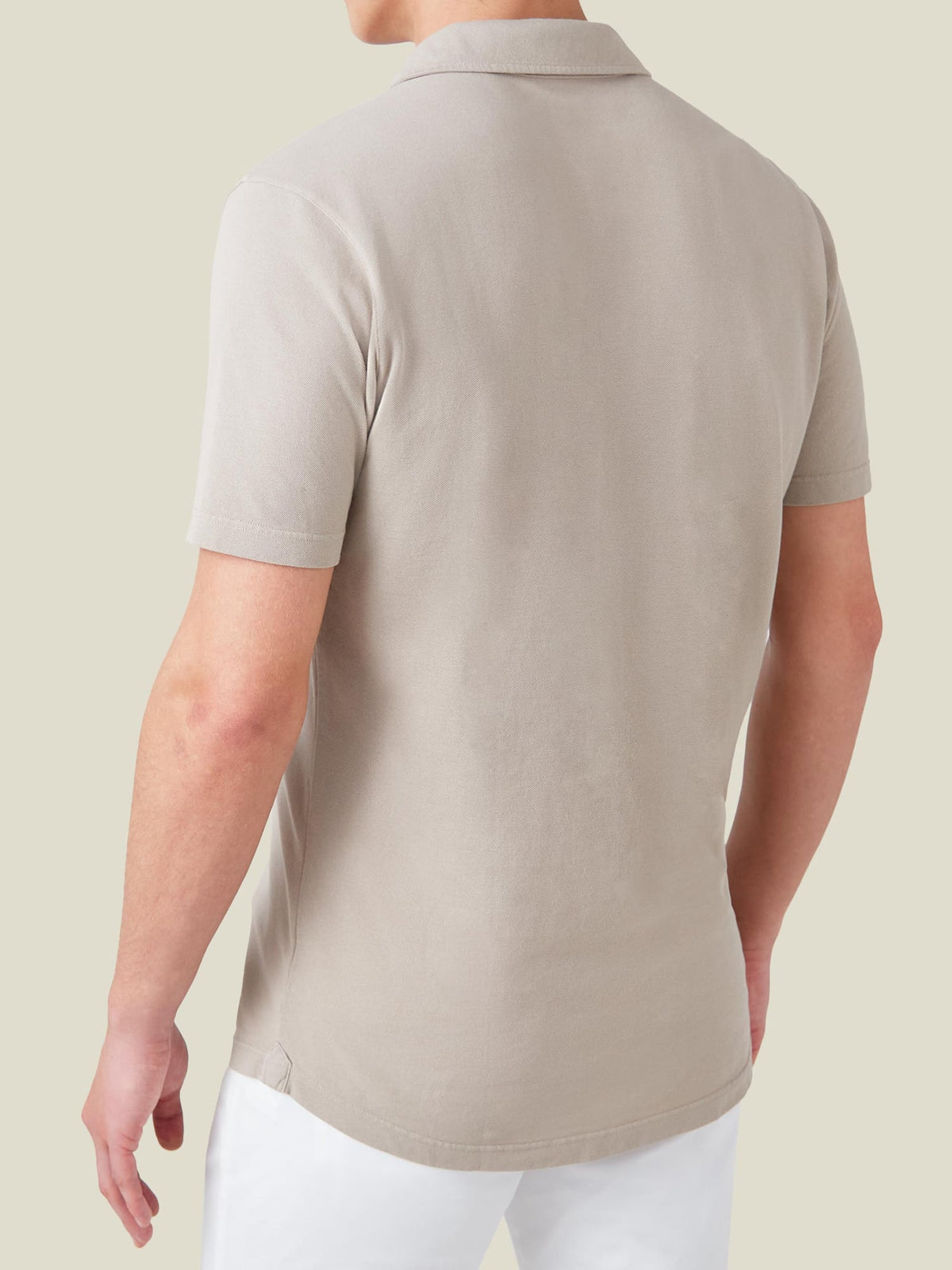 Rear view of a model wearing the Luca Faloni Classic Piqué Polo in oatmeal, showing the classic fit and rounded hem.