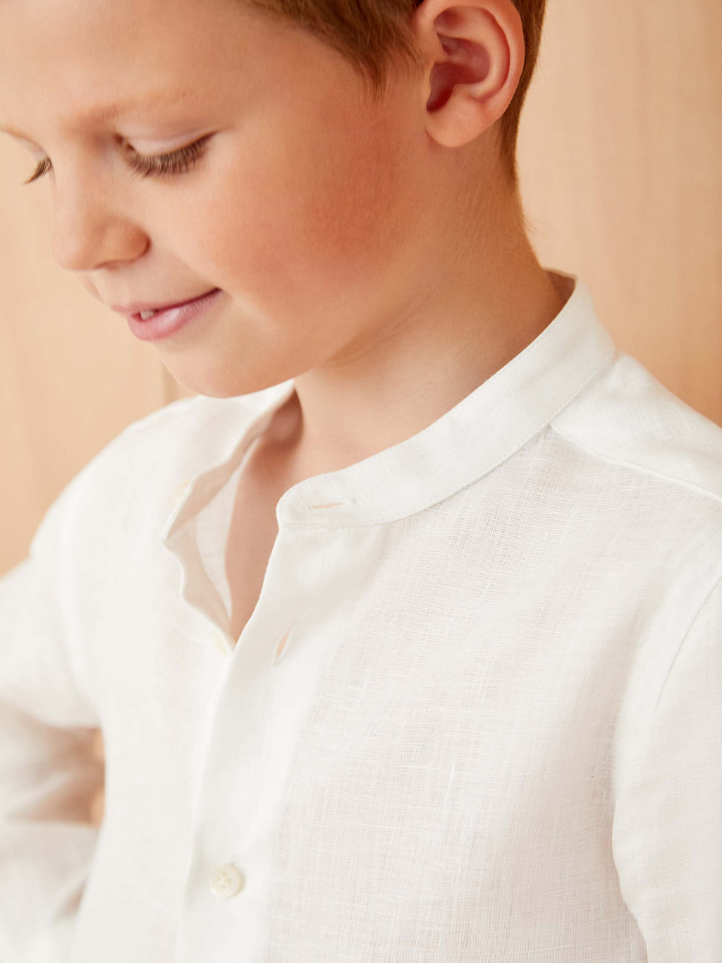 Close-up of a boy wearing the Luca Faloni white Versilia Junior linen shirt, showing the fine texture and band collar.