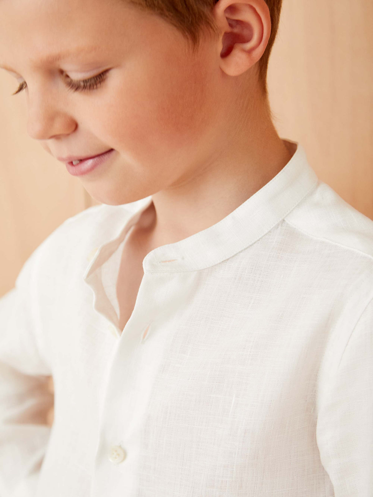 Close-up of a boy wearing the Luca Faloni white Versilia Junior linen shirt, showing the fine texture and band collar.