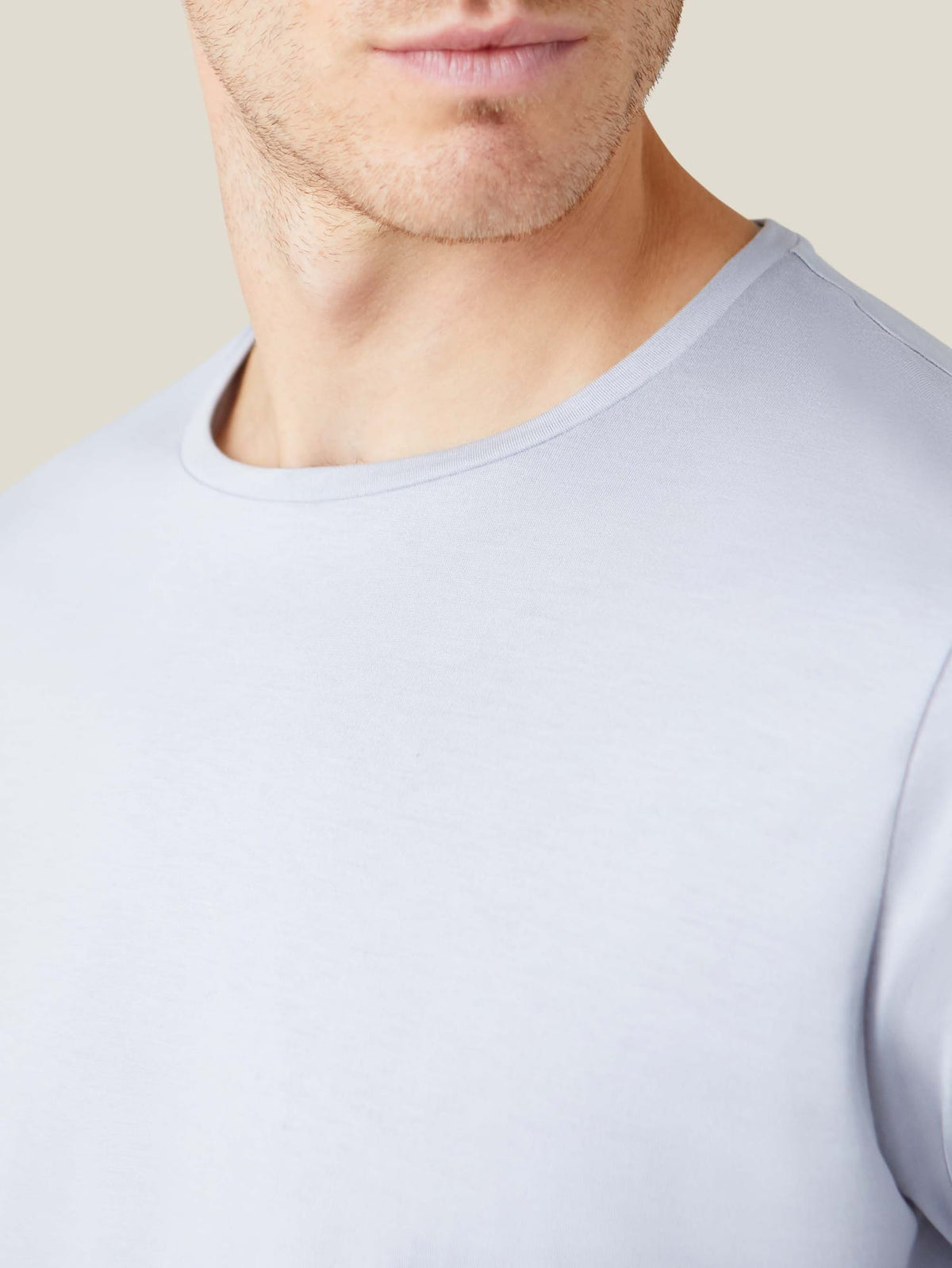 Detail of the crew neck and fine silk-cotton fabric of the light grey long-sleeved T-shirt.
