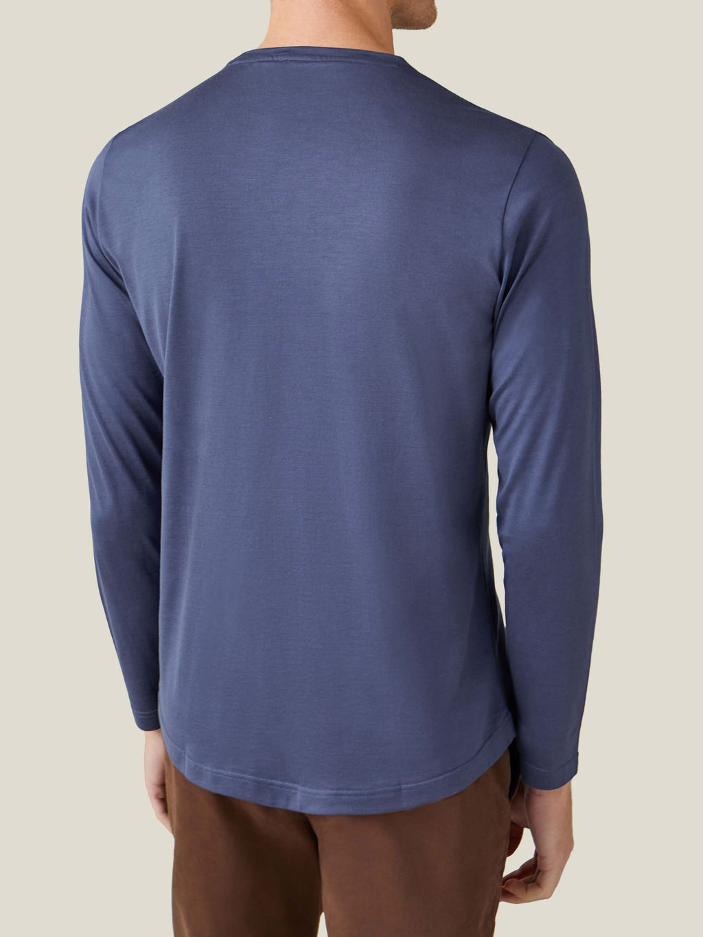 Back view of a man wearing the ocean blue silk-cotton long-sleeved T-shirt, highlighting the curved hem and relaxed fit.