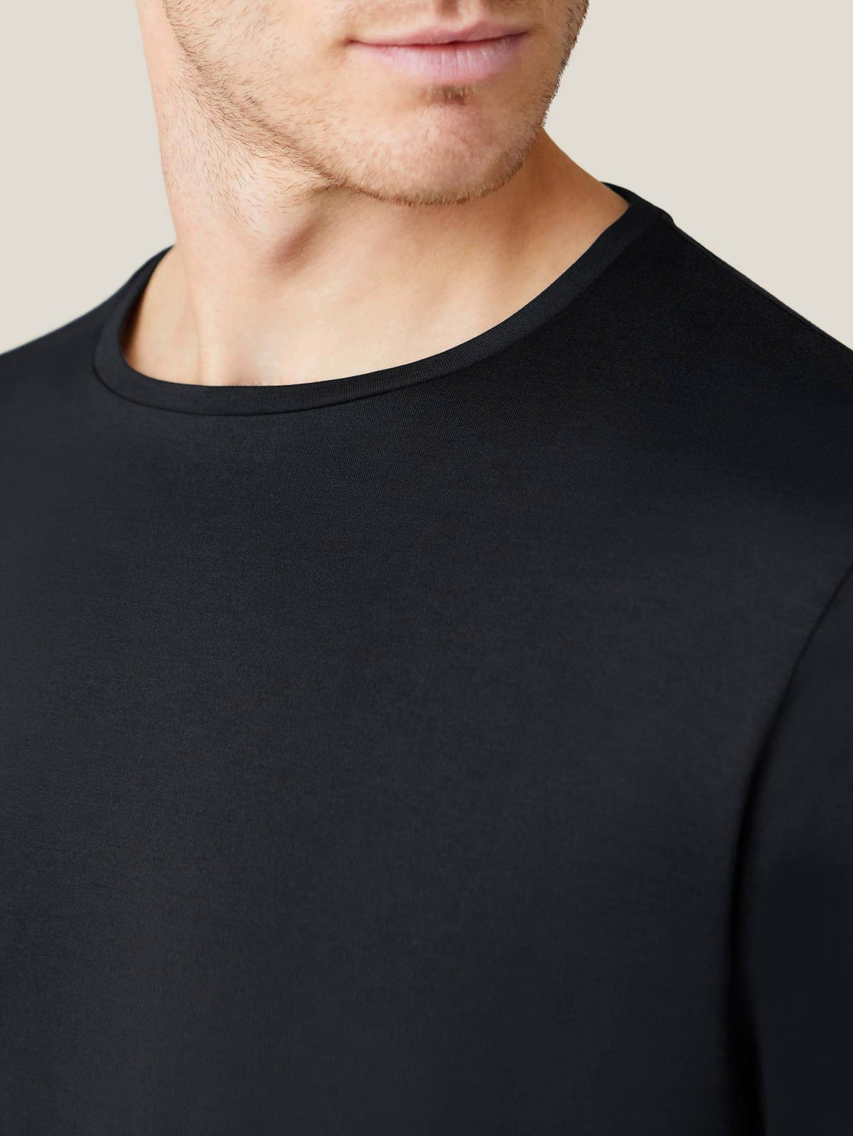 Close-up of the black silk-cotton long-sleeved T-shirt, highlighting the modern crew neckline and luxurious fabric.