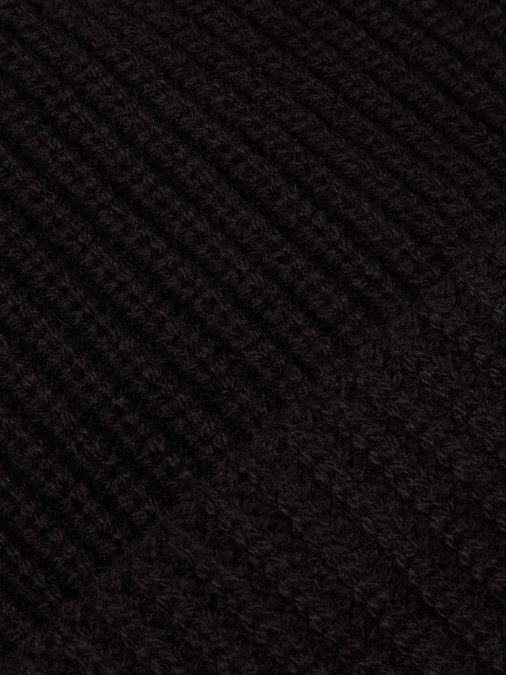 A close-up of the chunky ribbed knit texture of the black four-ply cashmere Chunky Knit Beanie.