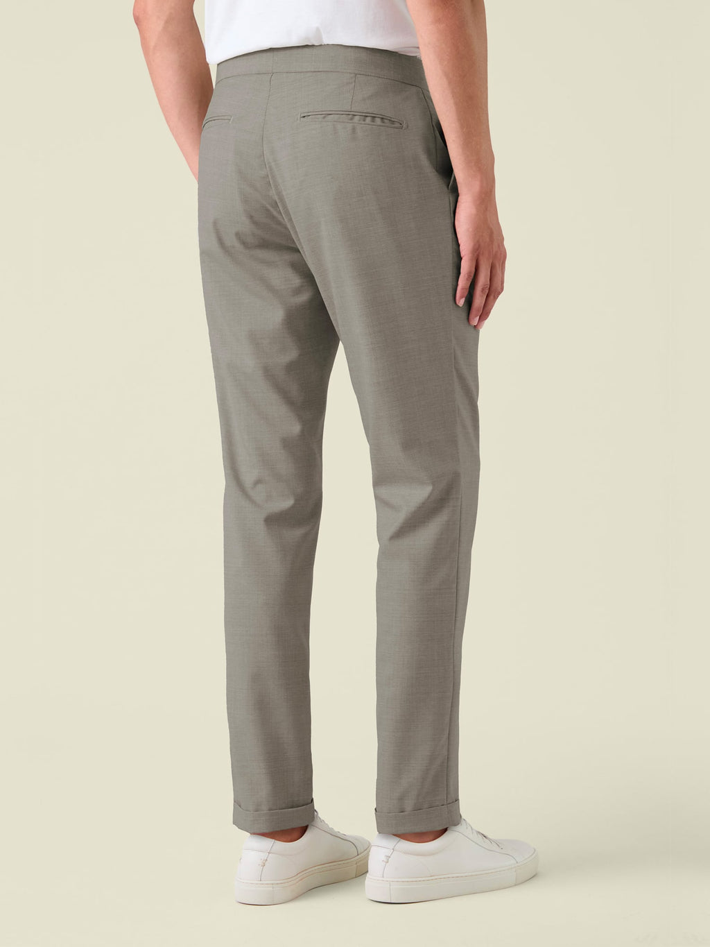 Back view of a model wearing the Lightweight Wool Trousers in Camel Beige, showing the tapered fit and cuffed hems.