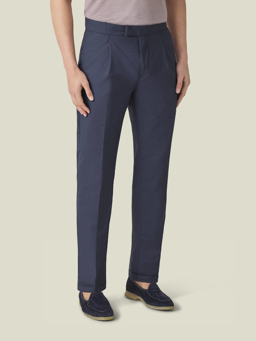 Front view of a model wearing Classic Blue Lightweight Wool Pleated Trousers, showcasing the tapered fit and cuffed hem.
