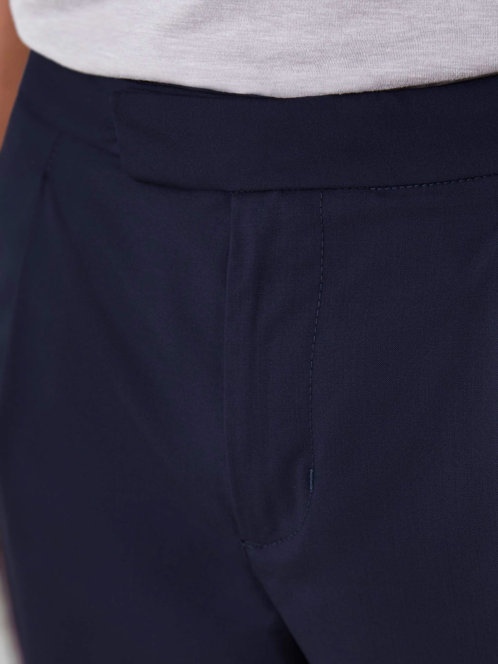 Close-up of the front of the Lightweight Wool Trousers in navy blue, detailing the waistband, single pleat, and fly closure.